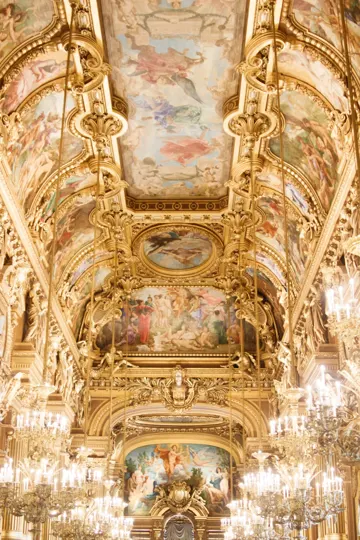 Ornate ceiling with gilded frescoes and chandeliers illuminates a grand hall.