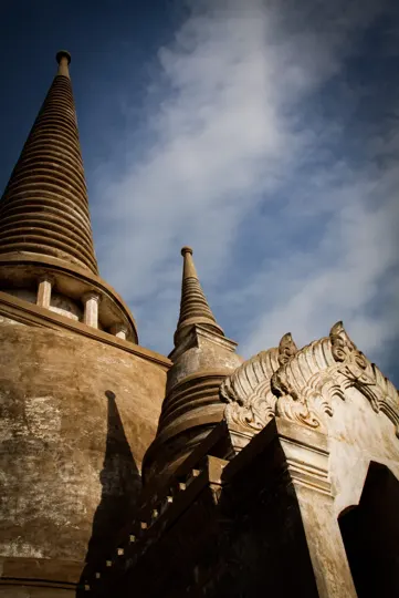 Ancient stone stupas rise under a dramatic sky, bathed in warm sunlight.