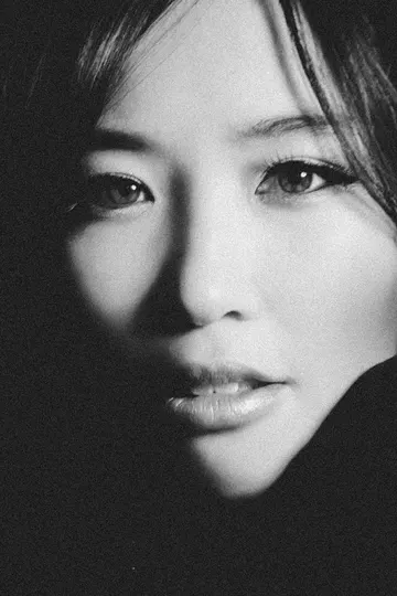 A woman's face partially illuminated, dark background, soft chiaroscuro.