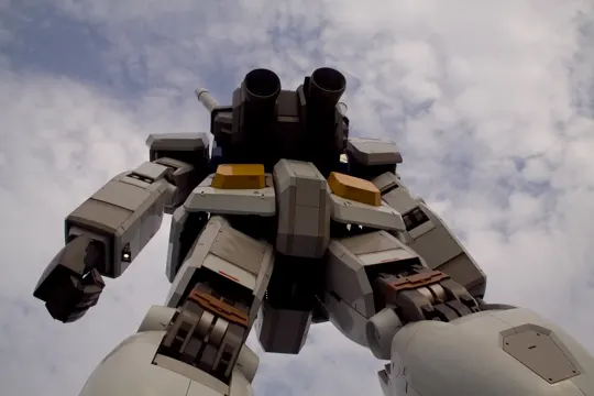 A towering mecha stands against a cloudy sky, its metallic form catching diffused light.