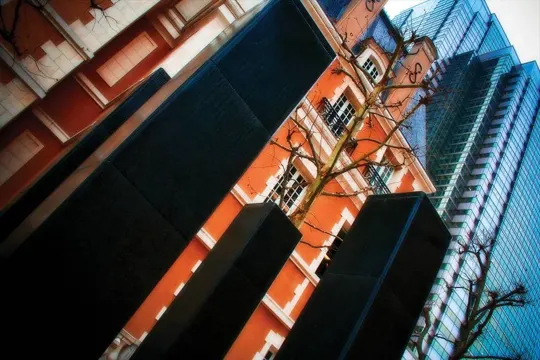 Urban contrast: historic orange building and modern glass tower under clear sky.
