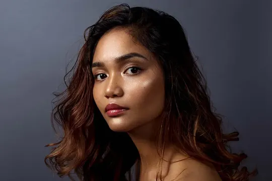 Loose waves cascade against a dark background, illuminated by soft, directional light.