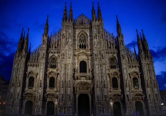 Gothic cathedral illuminated against twilight sky, intricate stonework bathed in soft evening light.