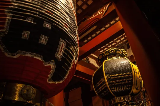Traditional lanterns illuminate a dimly lit, ornately decorated interior space.