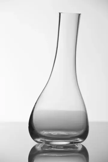 Clear glass carafe stands tall against a soft, diffused white background.