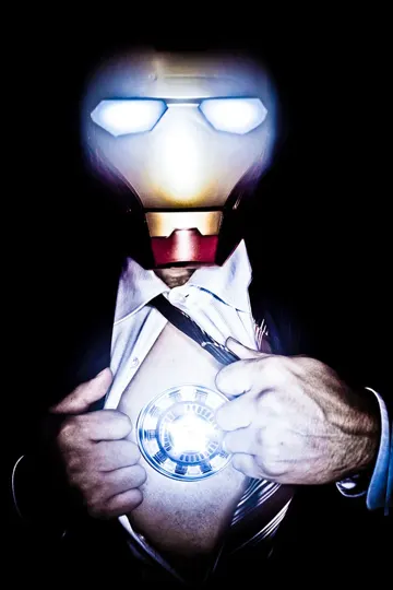 Subject in formal attire reveals glowing arc reactor against dark background.