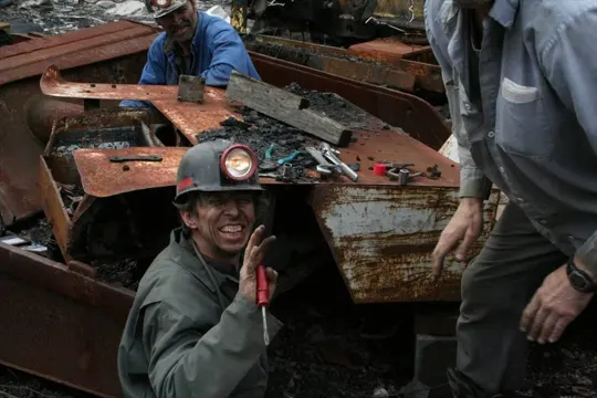 Workers examine rusted machinery amidst debris under diffused natural light.