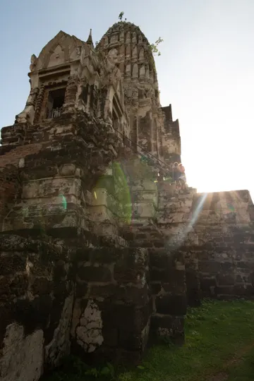 Sunlight pierces through ancient stone ruins, casting dramatic shadows.