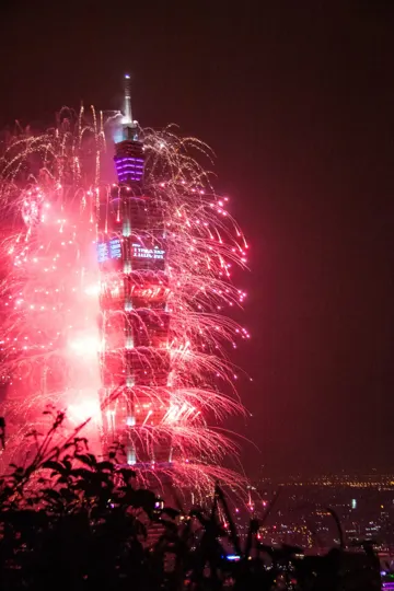 Illuminated tower surrounded by vibrant red fireworks against a dark night sky.