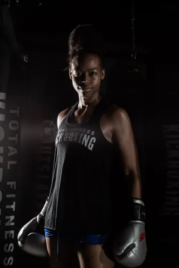 Athlete in boxing attire, dimly lit with gym equipment and "TOTAL FITNESS" visible.