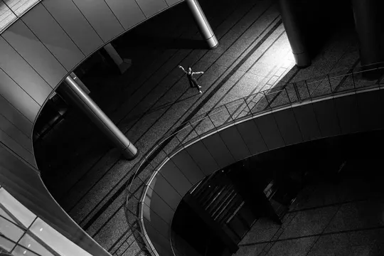 A dancer moves through a curved, industrial space with stark, directional light.